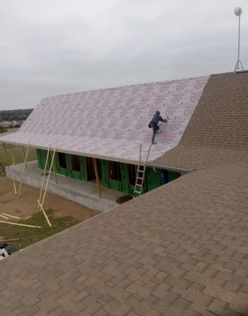 Worker preparing underlayment for a metal roof installation in Valencia West